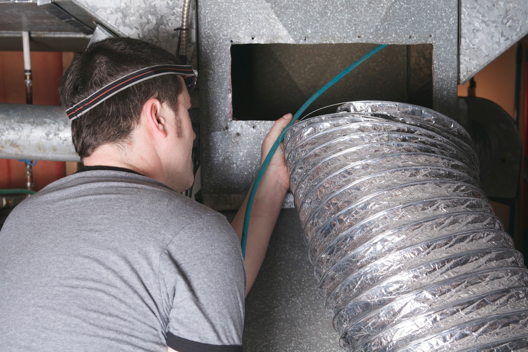 HVAC technician cleaning air ducts in home