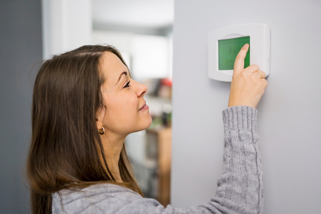 Homeowner setting thermostat during winter in Nebraska