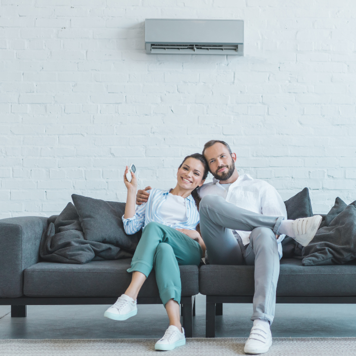 air conditioner above couple sitting on couch